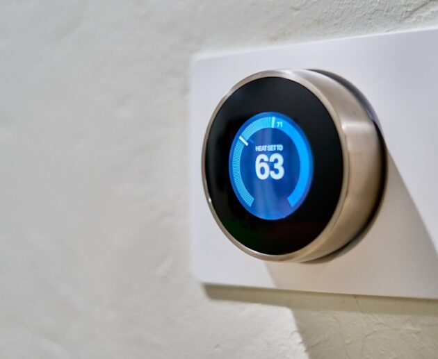 Smart thermostat mounted on a wall displaying the current temperature