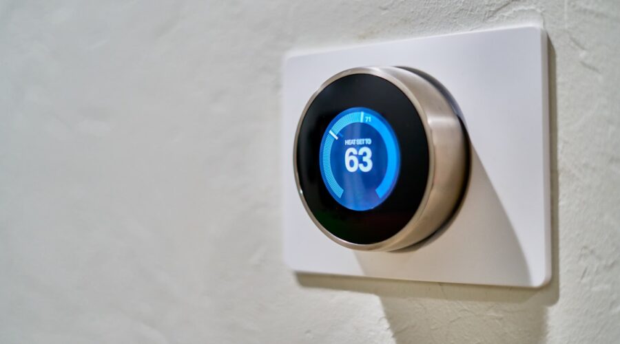 Smart thermostat mounted on a wall displaying the current temperature