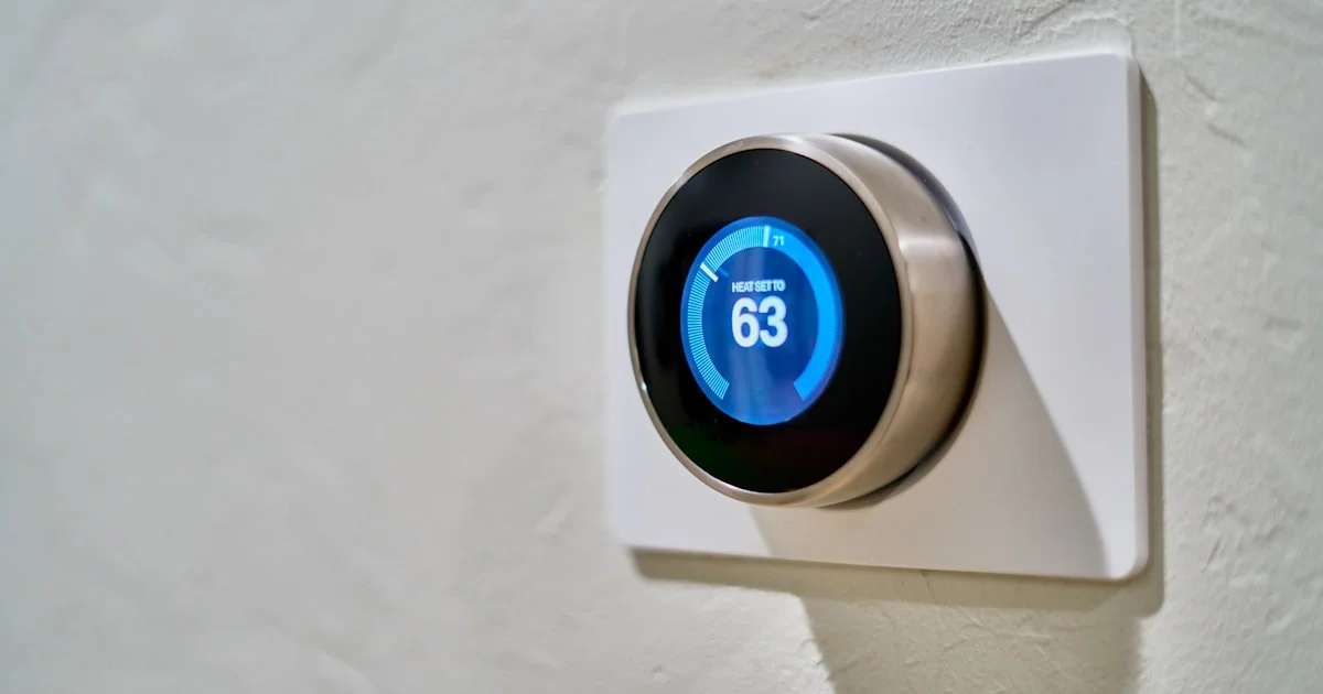 Smart thermostat mounted on a wall displaying the current temperature