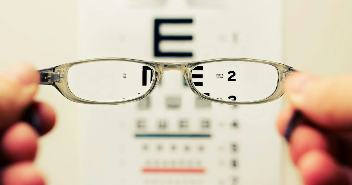 A pair of eyeglasses held in front of an eye chart, the prescription step behind any best eyeglasses online 2026 shortlist