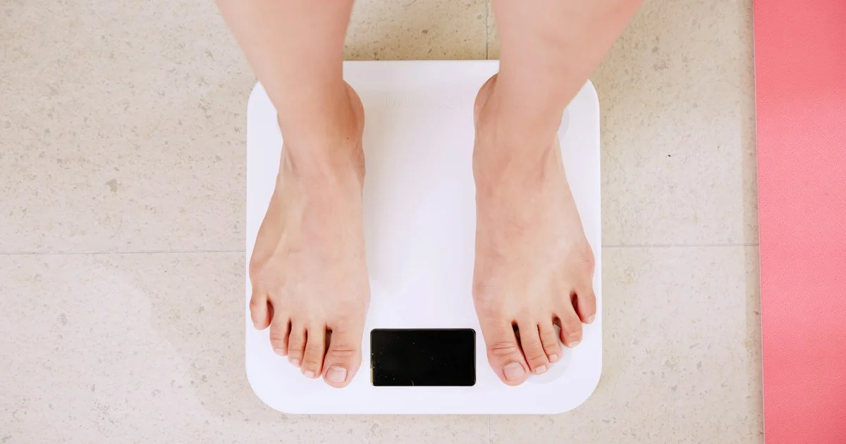 Bare feet standing on a white digital bathroom scale, the contact the best smart scale 2026 needs to read body composition