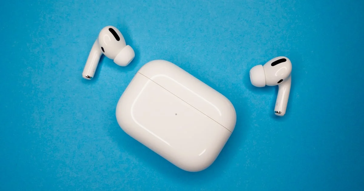 White wireless earbuds resting beside their charging case