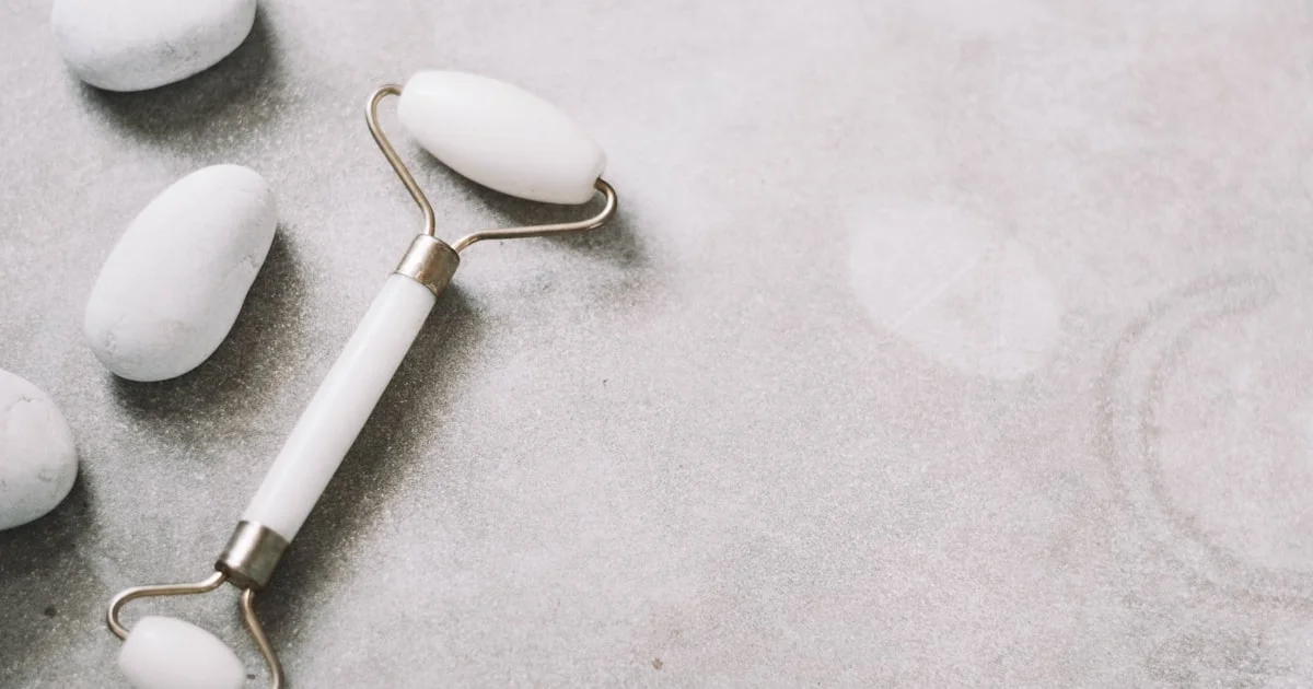 Jade facial roller tool on a stone surface
