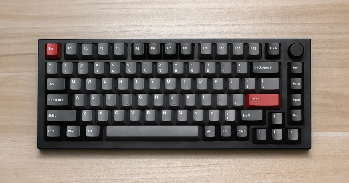 Mechanical gaming keyboard with grey and black keycaps on a wooden desk