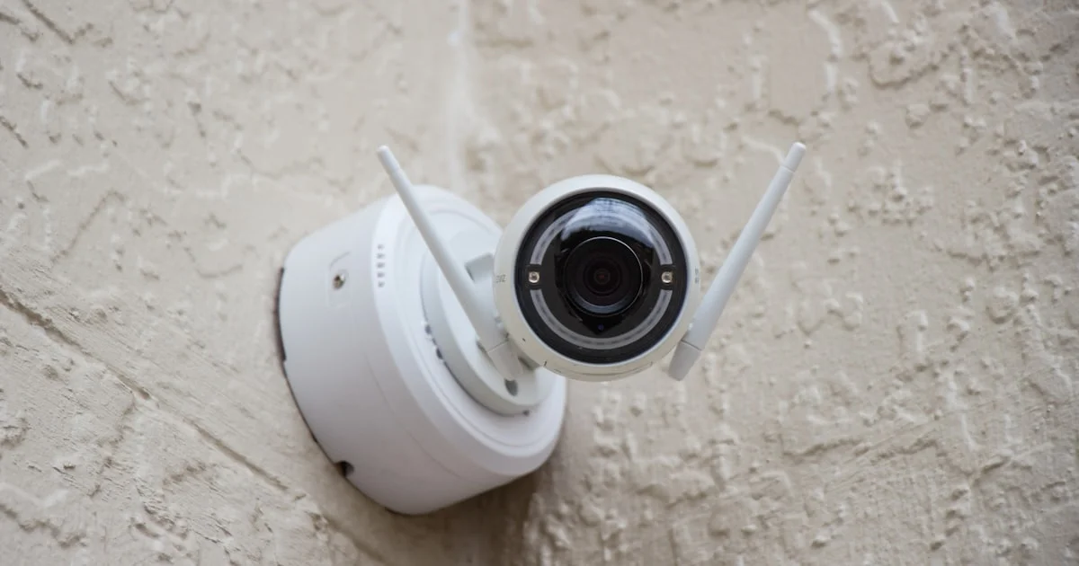 White WiFi smart home security camera with antennas mounted on an exterior wall