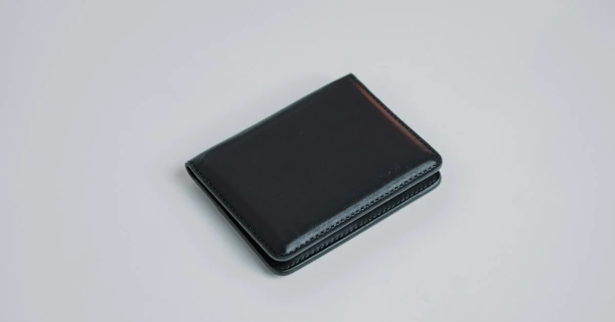 A plain black leather bifold wallet on a light surface, the ordinary starting point behind any top smart wallet 2026 decision