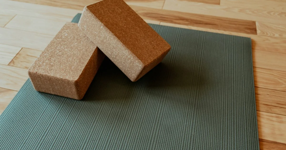 A plain ribbed yoga mat with two cork blocks on a wood floor, the ordinary setup the top smart yoga mat 2026 has to improve on