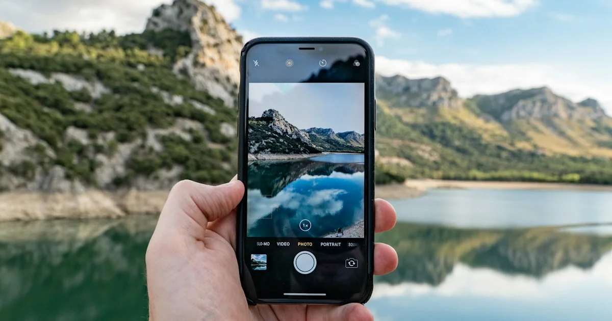 Hand holding a phone with the camera app open on a landscape, the growing photo library behind the question of which cloud storage app to buy in 2026