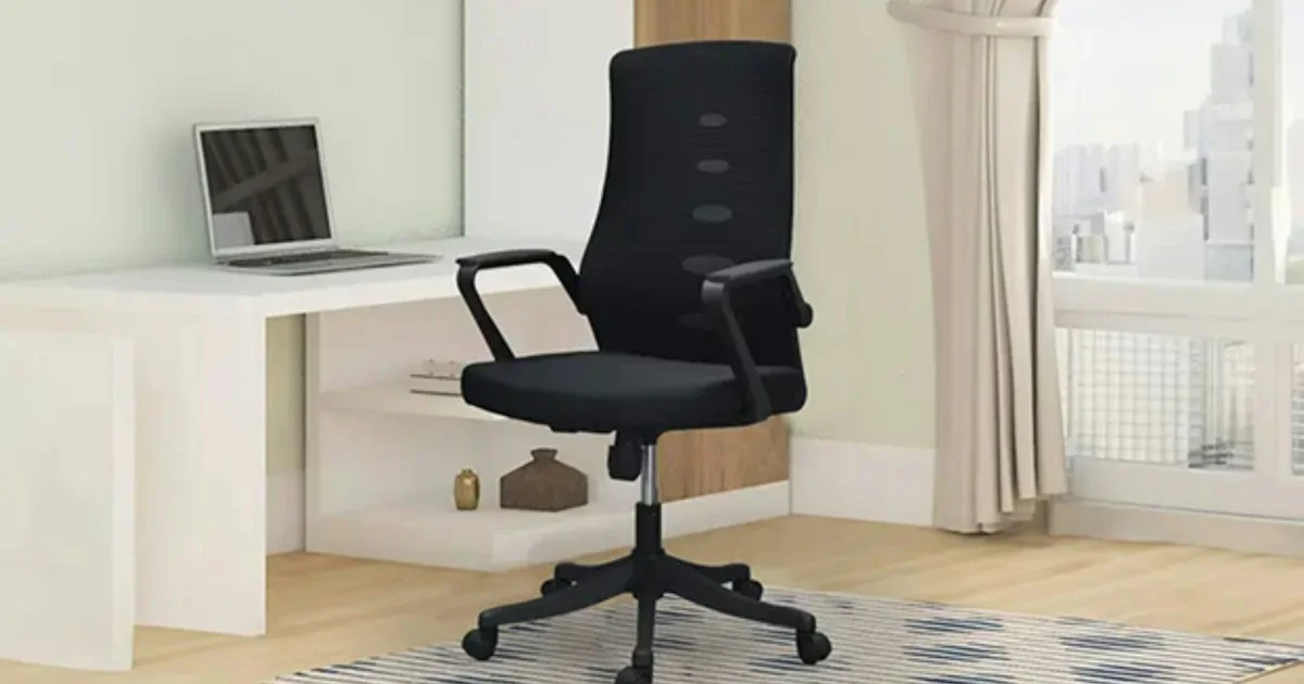 Black mesh-back task chair with a five-star base beside a home office desk, the kind of seat to weigh when deciding which ergonomic office chair to buy in 2026
