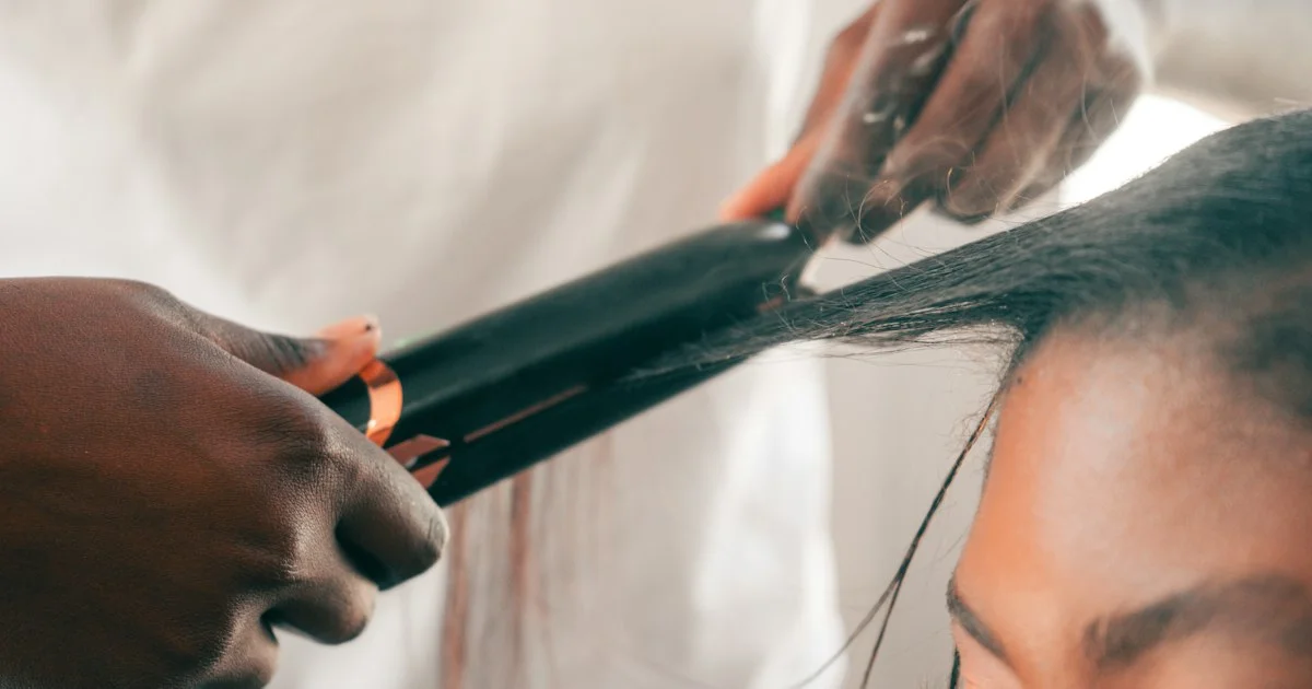 Working out which hair straightener should I buy: a flat iron closing on a smoothed section of dark hair