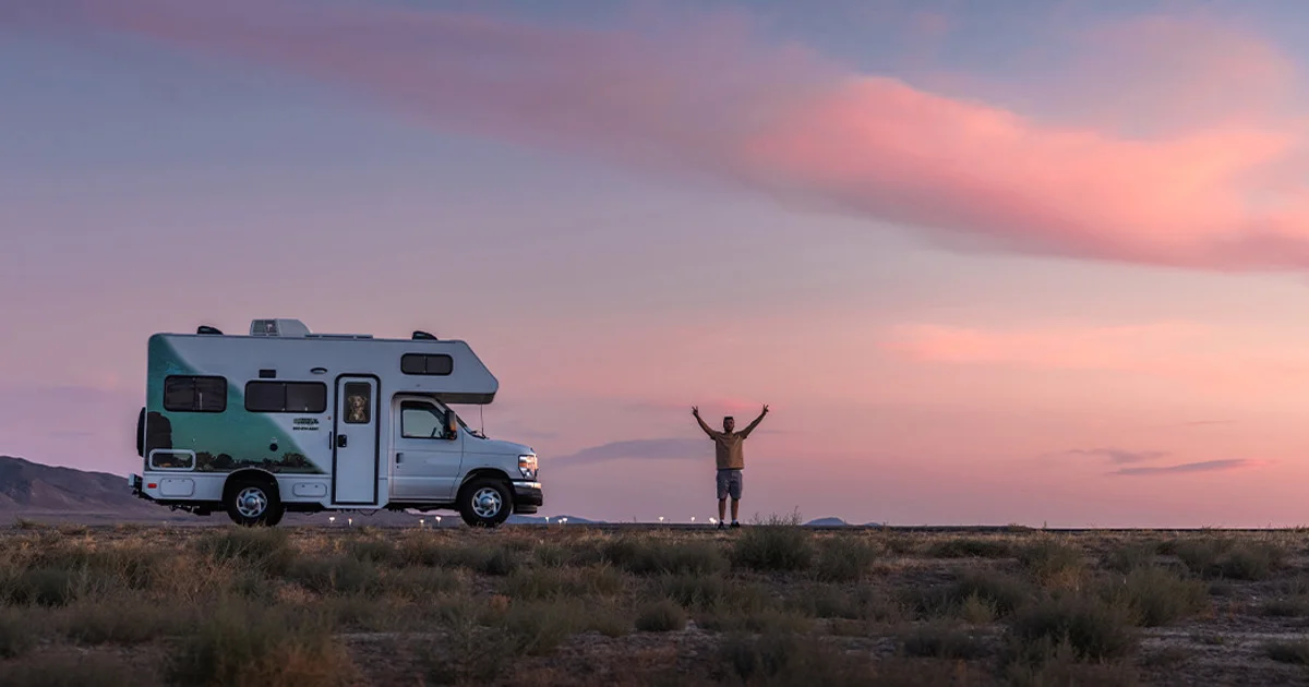 A Cruise America motorhome parked in open desert at dusk with a traveler standing nearby, the trip behind any best RV rental companies in 2026 comparison